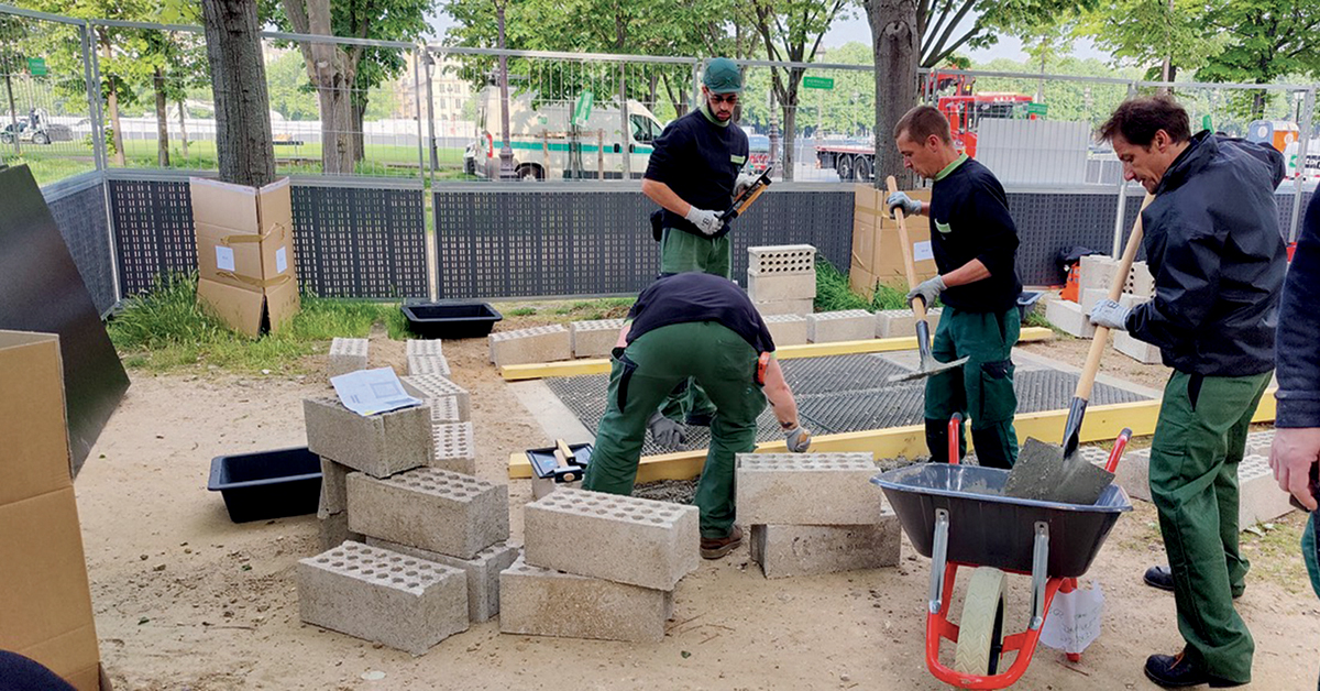 Une équipe d’agents RATP monte un mur de parpaings autour d’une bouche d’aération du métro, sur l’esplanade des Invalides.